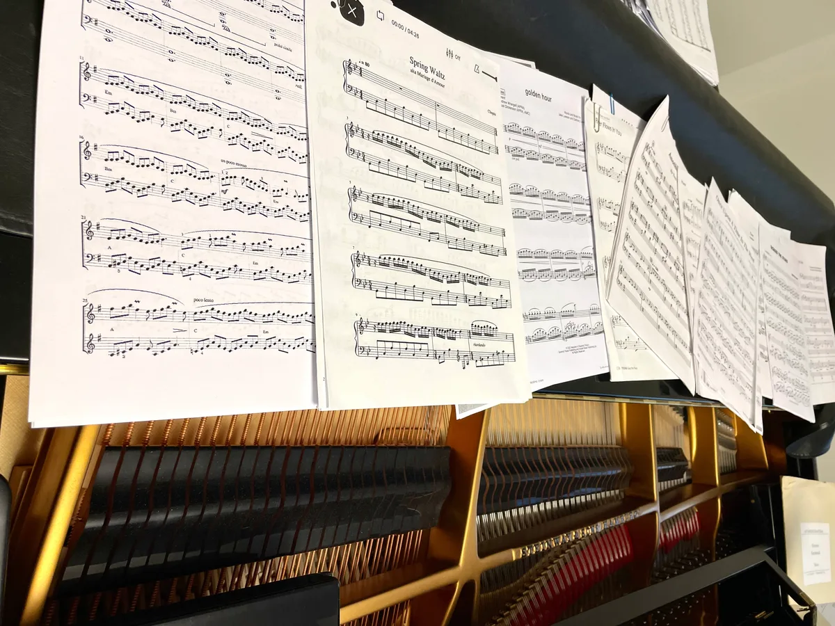 Musiknoten liegen überall verteilt auf dem Klavier.